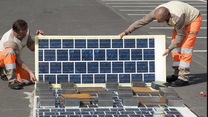 Εργάτες τοποθετούν επιφάνεια φωτοβολταϊκών σε δρόμο στη Γαλλία.