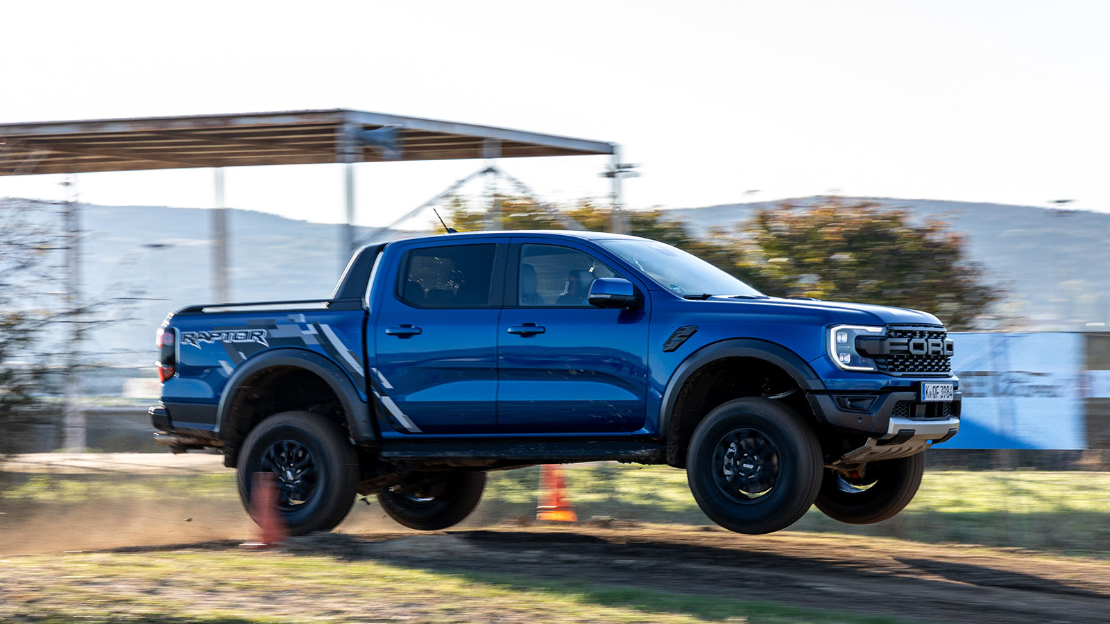 Ford Ranger Raptor σε χωμάτινη διαδρομή και Ford Ranger PHEV με τρέιλερ.