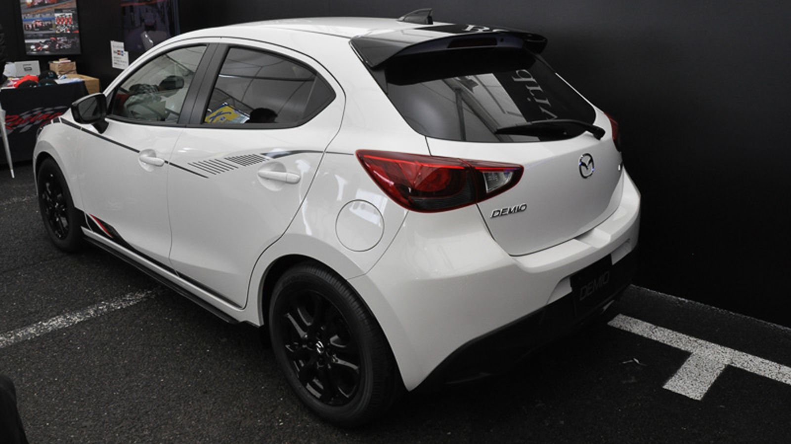 Επιπλέον αλλαγές του Demio Racing Concept σε σχέση με το «κανονικό» Mazda2 είναι η κεραία τύπου «πτερύγιο καρχαρία», οι αυτοκόλλητες ρίγες και μαύρα κ