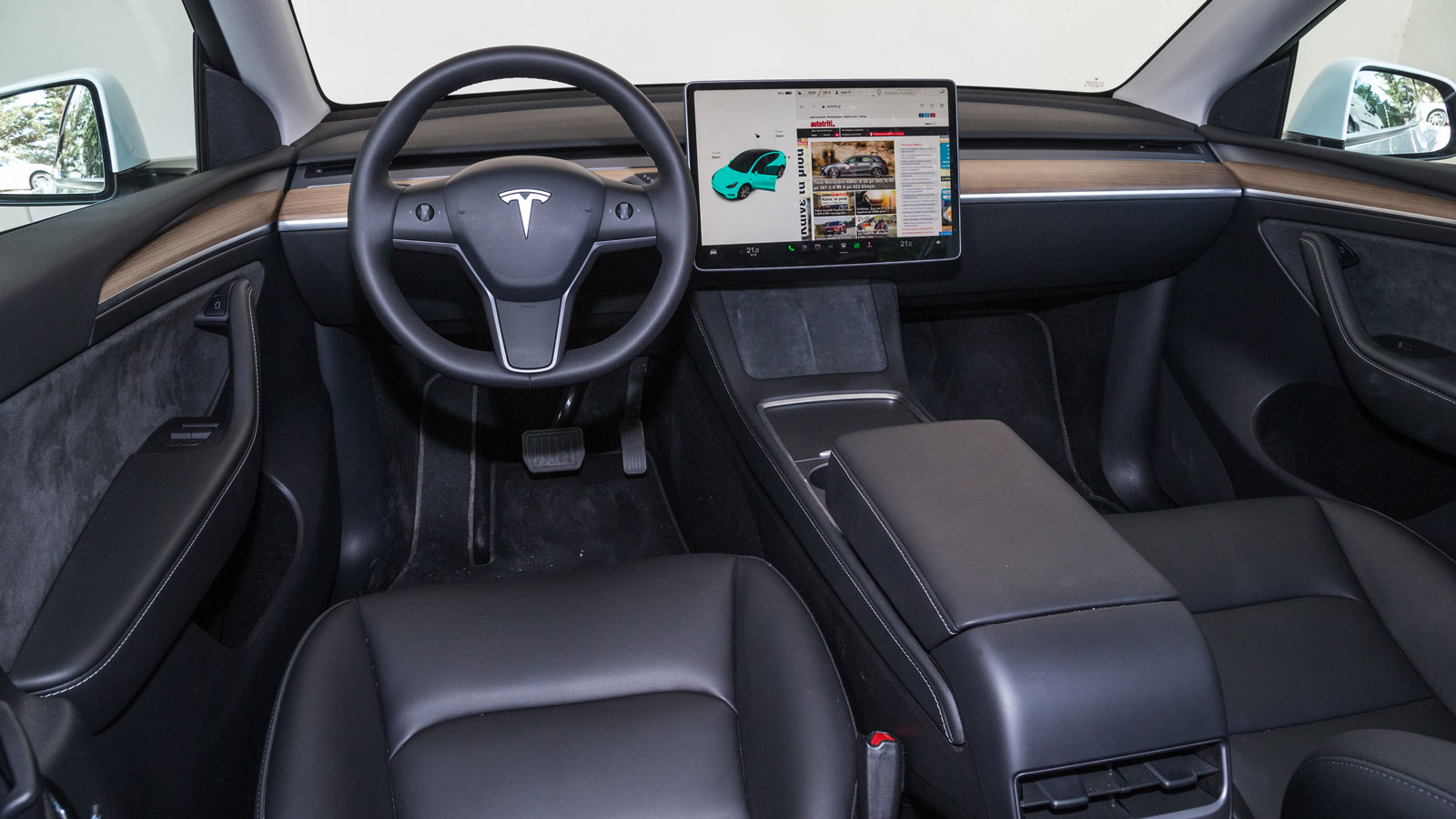 Στη minimal καμπίνα του Tesla Model Y οι φυσικοί διακόπτες λάμπουν δια της απουσίας τους, πέρα από δύο ροδέλες στο τιμόνι και τα αλάρμ εκεί που σε άλλ