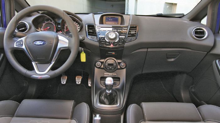 Διακριτικά σπορτίφ το εσωτερικό του Ford Fiesta ST, με λογότυπα «ST» και αλουμίνιο στις επενδύσεις. Διακριτικά σπορτίφ το εσωτερικό του Ford Fiesta ST, με λογότυπα «ST» και αλουμίνιο στις επενδύσεις.