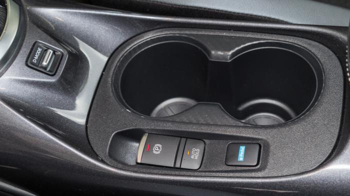 Ανάμεσα στα καθίσματα βρίσκεται το κουμπί για το e-pedal: Mόλις το επιλέξεις το αυτοκίνητο φρενάρει πιο έντονα στο άφημα του γκαζιού, όχι όμως όσο στο αμιγώς ηλεκτρικό  LEAF. 